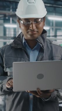 Dikey Portre Mühendisi Otomobil Fabrikasında dizüstü bilgisayarda çalışıyor.