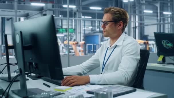 Ingeniero que trabaja en la computadora de escritorio en la fábrica de automóviles — Vídeo de stock