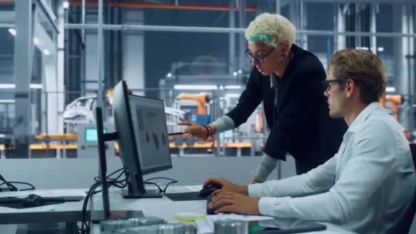 Два инженера, работающие над проектированием электромобиля на настольном компьютере — стоковое видео