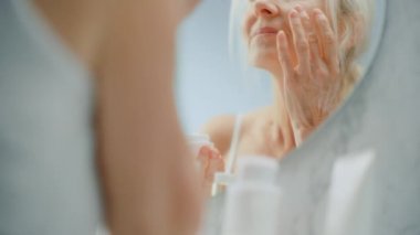 Kıdemli Kadın Yüz Kremi Aynası Kullanıyor