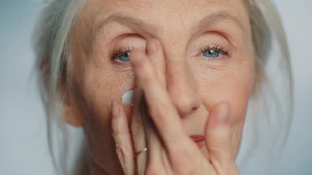 Ηλικιωμένη γυναίκα ομορφιά χρησιμοποιεί κρέμα ματιών — Αρχείο Βίντεο