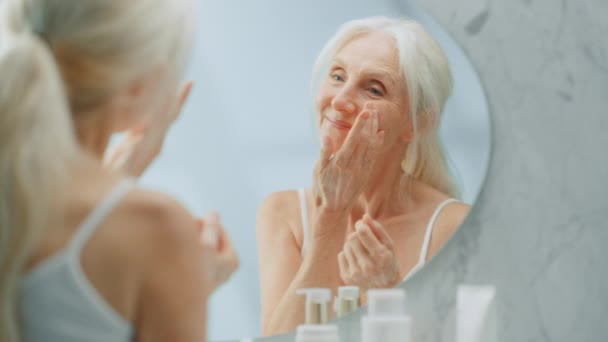Senior kvinna som använder ansiktskräm spegel — Stockvideo