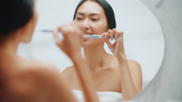Νεαρή ενήλικη γυναίκα βουρτσίζει τα δόντια στον καθρέφτη — Αρχείο Βίντεο