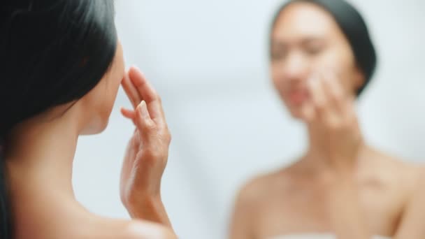 Женщина использует крем для лица в зеркале — стоковое видео
