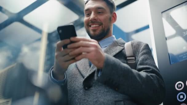 Uomo d'affari cavalcare ascensore utilizzando Smartphone — Video Stock