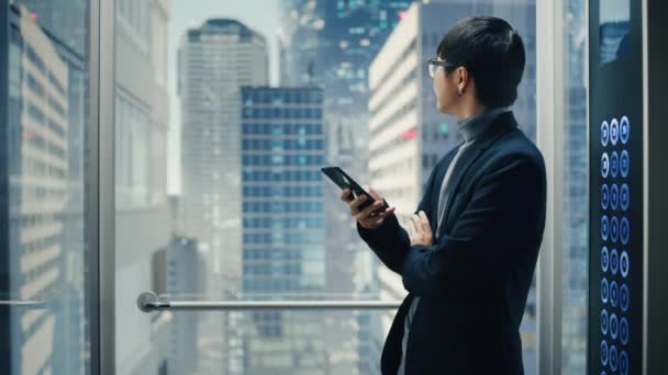 Японський бізнесмен, який їздить на ліфті за допомогою смартфона — стокове відео