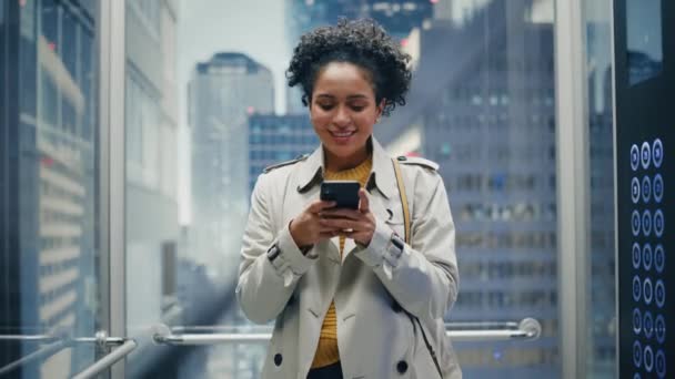 Latina feminino equitação elevador para o escritório usando Smartphone — Vídeo de Stock