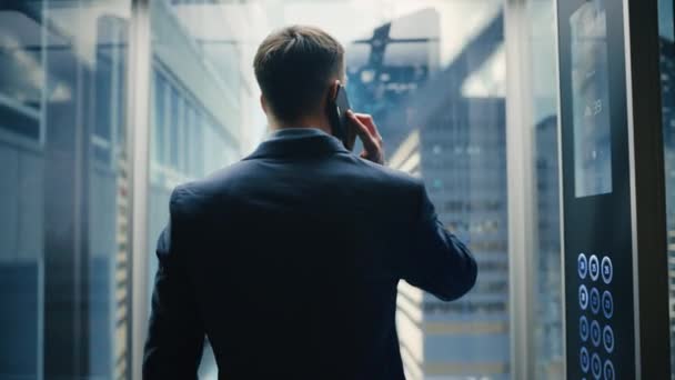 Forretningsmand Riding Elevator Taler på Smartphone – Stock-video