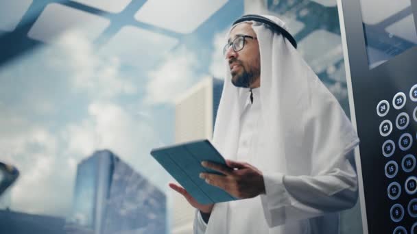 Арабский бизнесмен едет на лифте с помощью планшета — стоковое видео