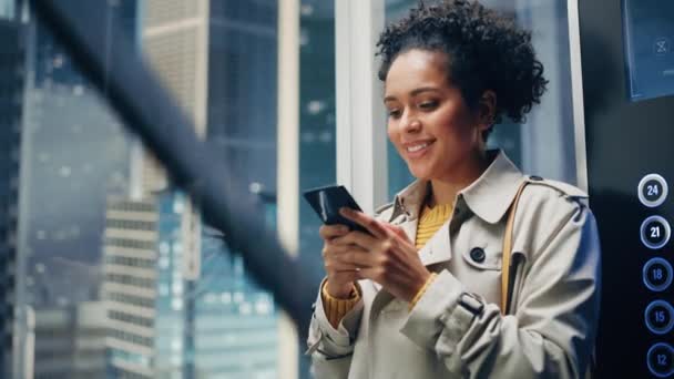 Latina femminile cavalcare ascensore per ufficio utilizzando Smartphone — Video Stock