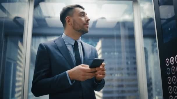 Zakenman rijden Lift met behulp van Smartphone — Stockvideo