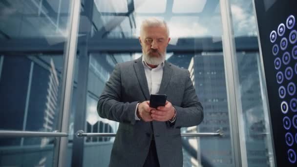 Hombre de negocios de la Edad Media que monta el elevador usando Smartphone — Vídeo de stock