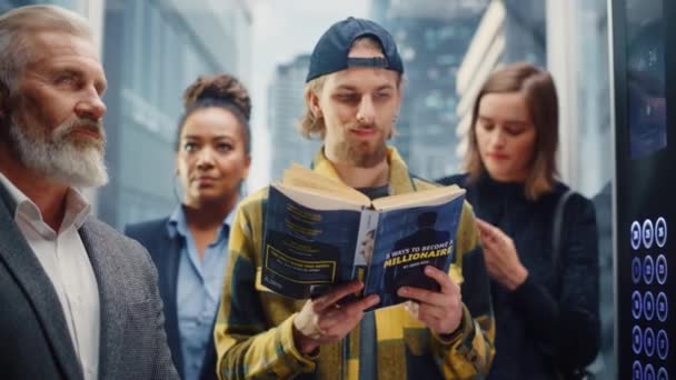 Junger Mann fährt Fahrstuhl und liest Buch — Stockvideo