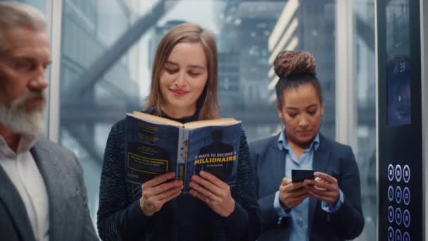 Female Riding Elevator Reading Book — Stock Video