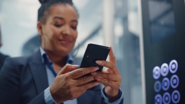 Schwarze Fahrstuhlfahrerin fährt mit Smartphone ins Büro — Stockvideo
