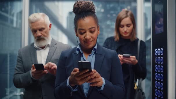 Diverse forretningsfolk i Elevator Brug Smartphones – Stock-video
