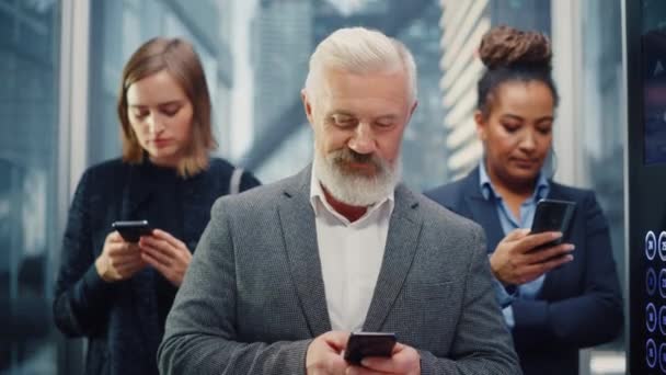 Различные бизнесмены в лифте с помощью смартфонов — стоковое видео