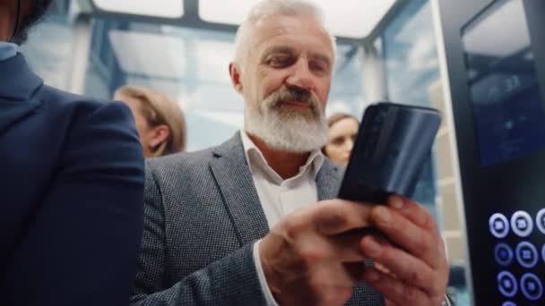 Hombre de negocios de la Edad Media que monta el elevador usando Smartphone — Vídeos de Stock