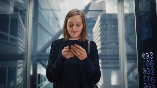 Feminino equitação elevador para o escritório usando Smartphone — Vídeo de Stock