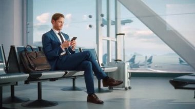 İşadamı havaalanında bekleyen akıllı telefon kullanıyor.