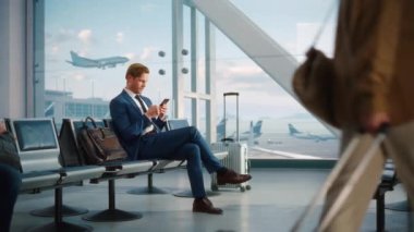 İşadamı havaalanında bekleyen akıllı telefon kullanıyor.