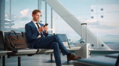 İşadamı havaalanında bekleyen akıllı telefon kullanıyor.