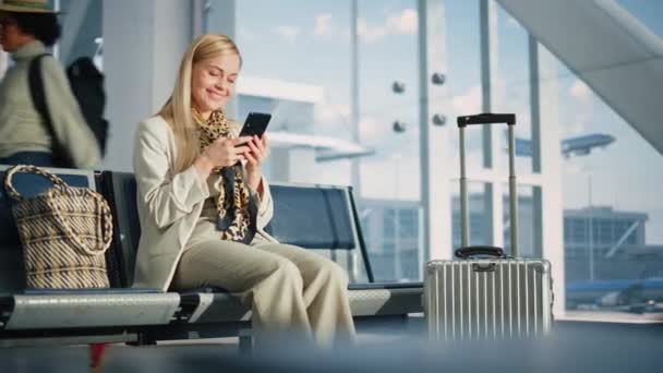 Kobieta korzystająca ze smartfona czeka na lot w terminalu lotniska — Wideo stockowe