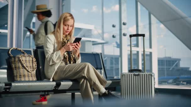 Vrouw met Smartphone wachtend op vlucht in luchthaventerminal — Stockvideo