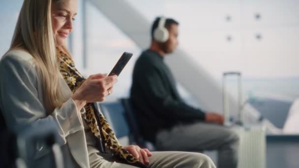 Frau wartet mit Smartphone im Flughafen-Terminal auf Flug — Stockvideo