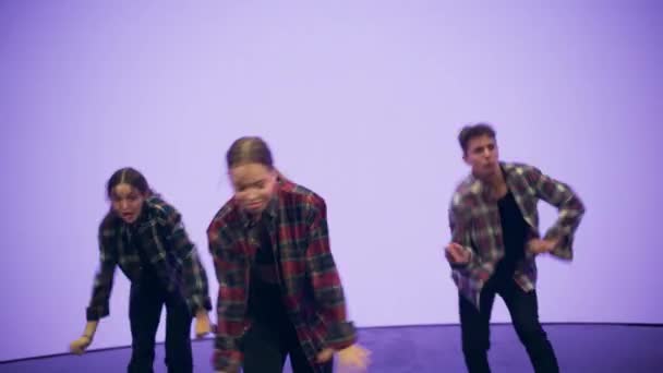 Nahaufnahme von drei Tänzern, die vor einem animierten digitalen Bildschirm auftreten — Stockvideo