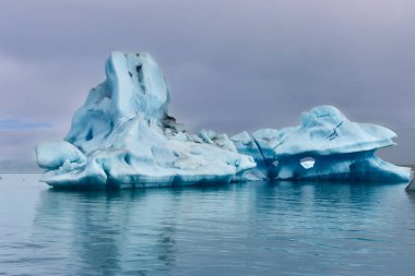 Jokulsarlon lagünündeki sakin sularda yüzen izole buzdağı.