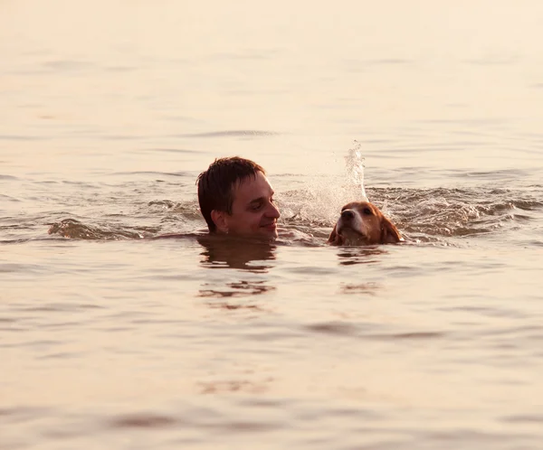 'S avonds zonsondergang: jongen met puppy in golven — Stockfoto