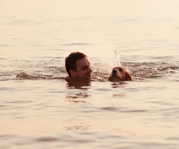 Tramonto di sera: ragazzo con il cucciolo in onde — Foto Stock