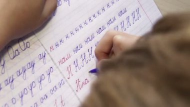 yazılı olarak ilk adımlar: küçük çocuk diyagonal çizgili defter içinde mektup yazıyor