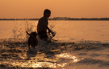 Okyanusu günbatımı dalga dalga geçmeyi beagle köpek yavrusu olan adam