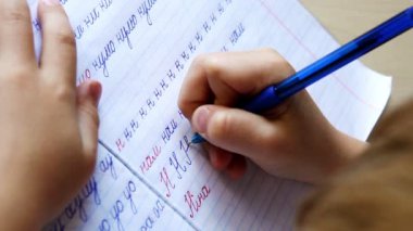 yazılı olarak ilk adımlar: küçük çocuk diyagonal çizgili defter içinde mektup yazıyor