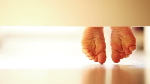Pair of gently child's feet on the laminate flooring : unusual UNDERbed view — Stock Video