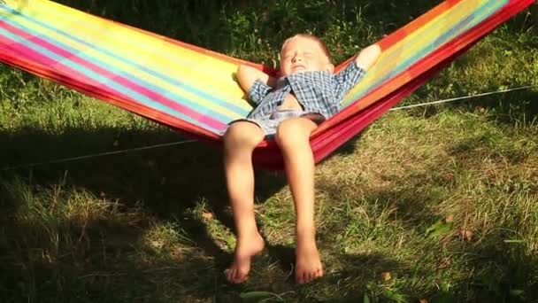 Little Boy enjoys warm sun rays in hammock — Stock Video