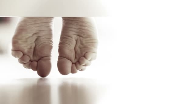 Pereche de picioare ușor de copil pe pardoseala laminată: vedere neobișnuită la pat — Videoclip de stoc