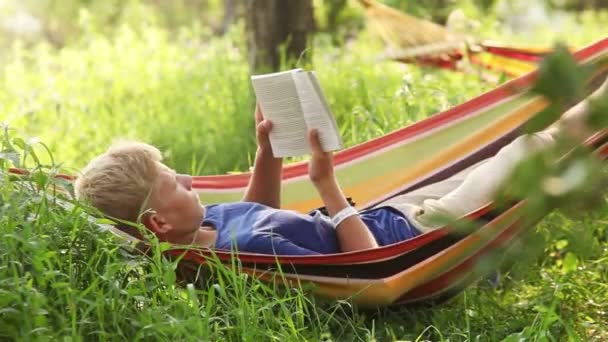 Reading last bestseller in cosy Hammock in apple trees shadows — Stock Video