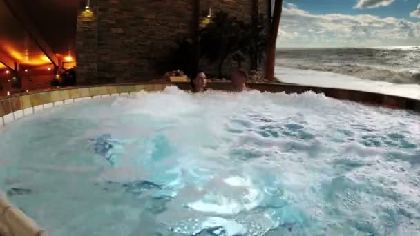 Jong paar in de jacuzzi op het tropische spa resort — Stockvideo