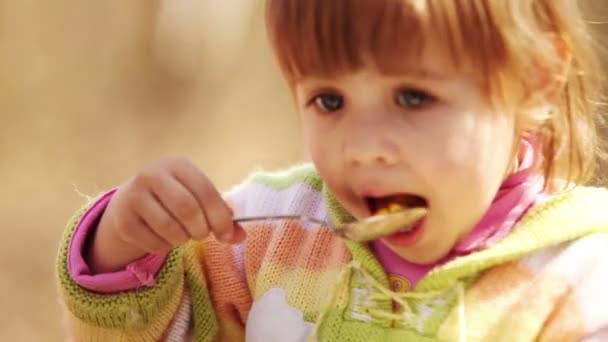 venkovní portrét: roztomilá holčička jí se lžičkou