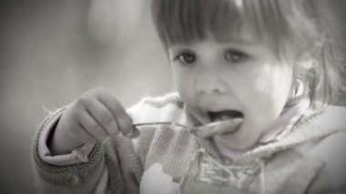 siyah beyaz portre: sevimli küçük kız kaşık ile eats