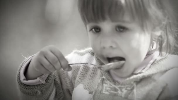 Schwarz-weiß Portrait: niedliche kleine Mädchen isst mit Löffel — Stockvideo