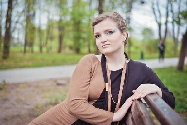 Junges Mädchen sitzt auf einer Bank — Stockfoto