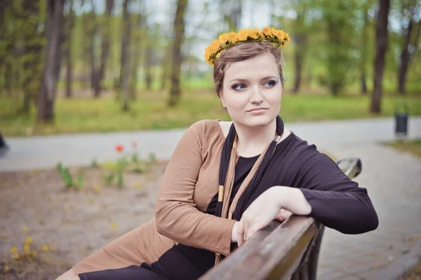 Başında sarı çiçek çelenk ile oturan kız — Stok fotoğraf