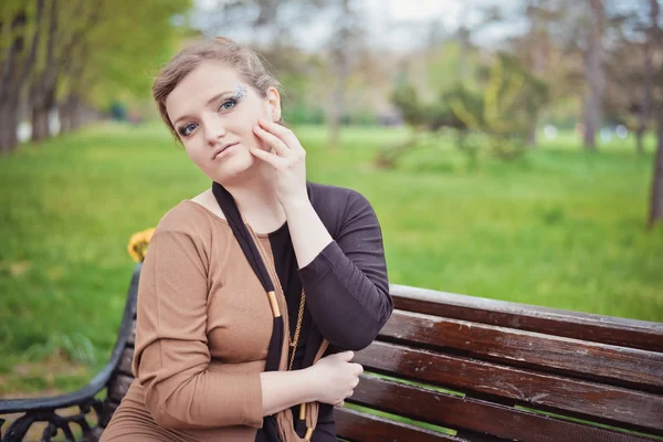 Jeune fille assise sur un banc — Photo