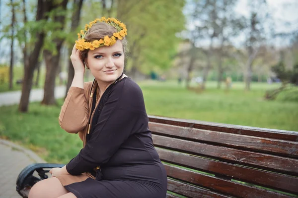 Fille assise avec une couronne de fleurs jaunes sur la tête — Photo