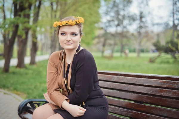 Fille assise avec une couronne de fleurs jaunes sur la tête — Photo