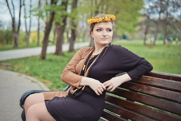 Başında sarı çiçek çelenk ile oturan kız — Stok fotoğraf